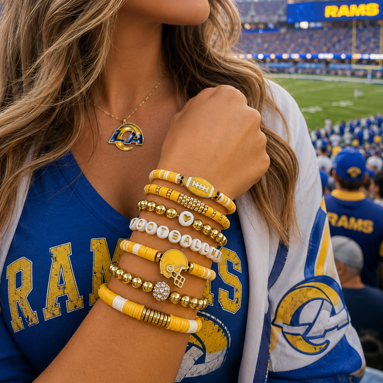 Person wearing Rams-themed jewelry and clothing at a sports event BRACELETS GOLDEN AND FOOTBALL MOM ON THE BEADS