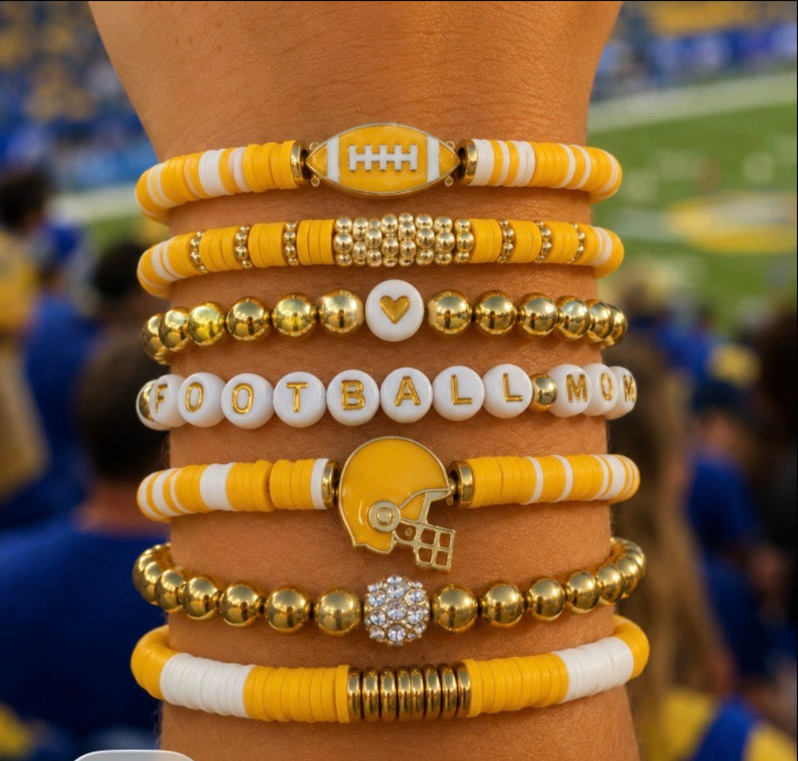 Stack of sports-themed bracelets on a wrist with a blurred sports event background FOOTBALL MOM