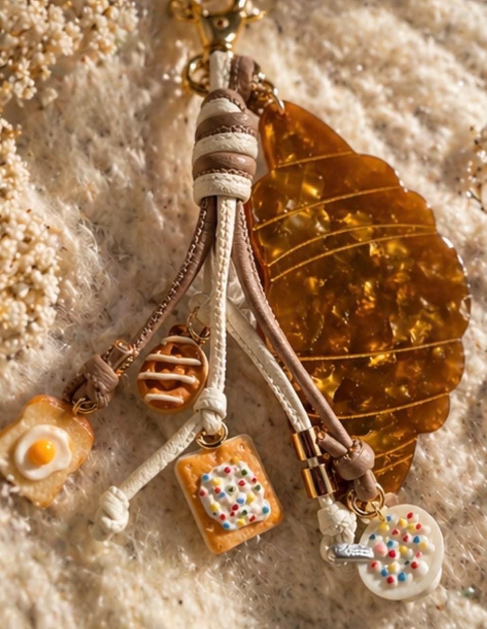 Decorative keychain with charms on a textured surface. Croissant and bruch charms for purse  
