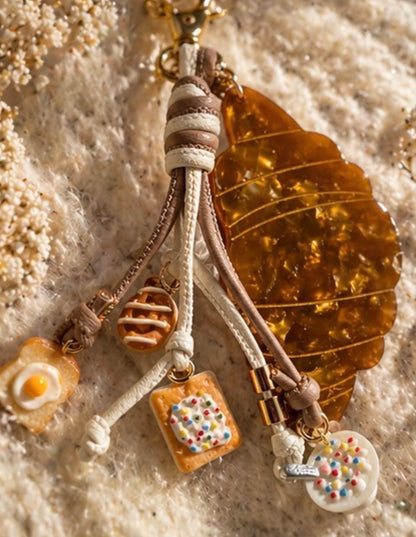 Decorative keychain with charms on a textured surface. Croissant and bruch charms for purse  