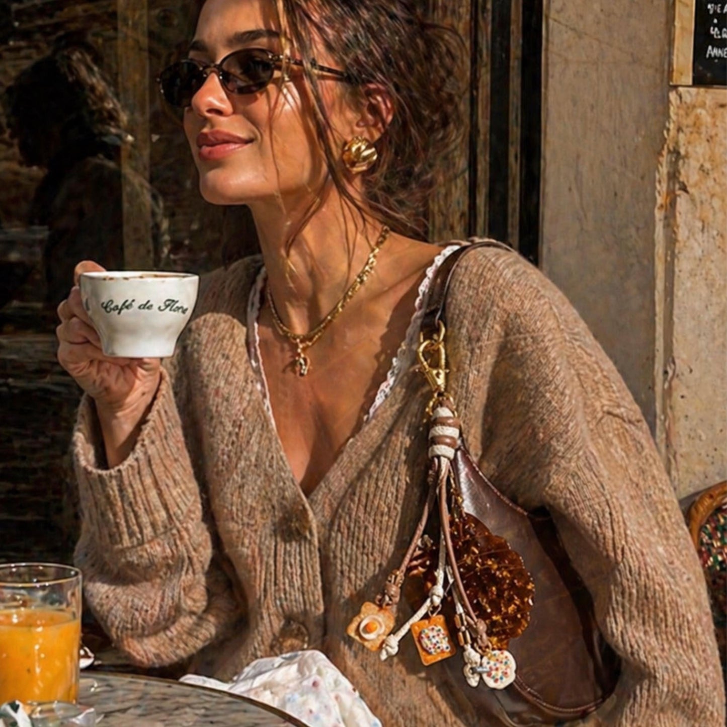 Woman in a cozy setting holding a coffee cup, wearing sunglasses and a brown sweater. Croissant  with breakfast brunch charms 
