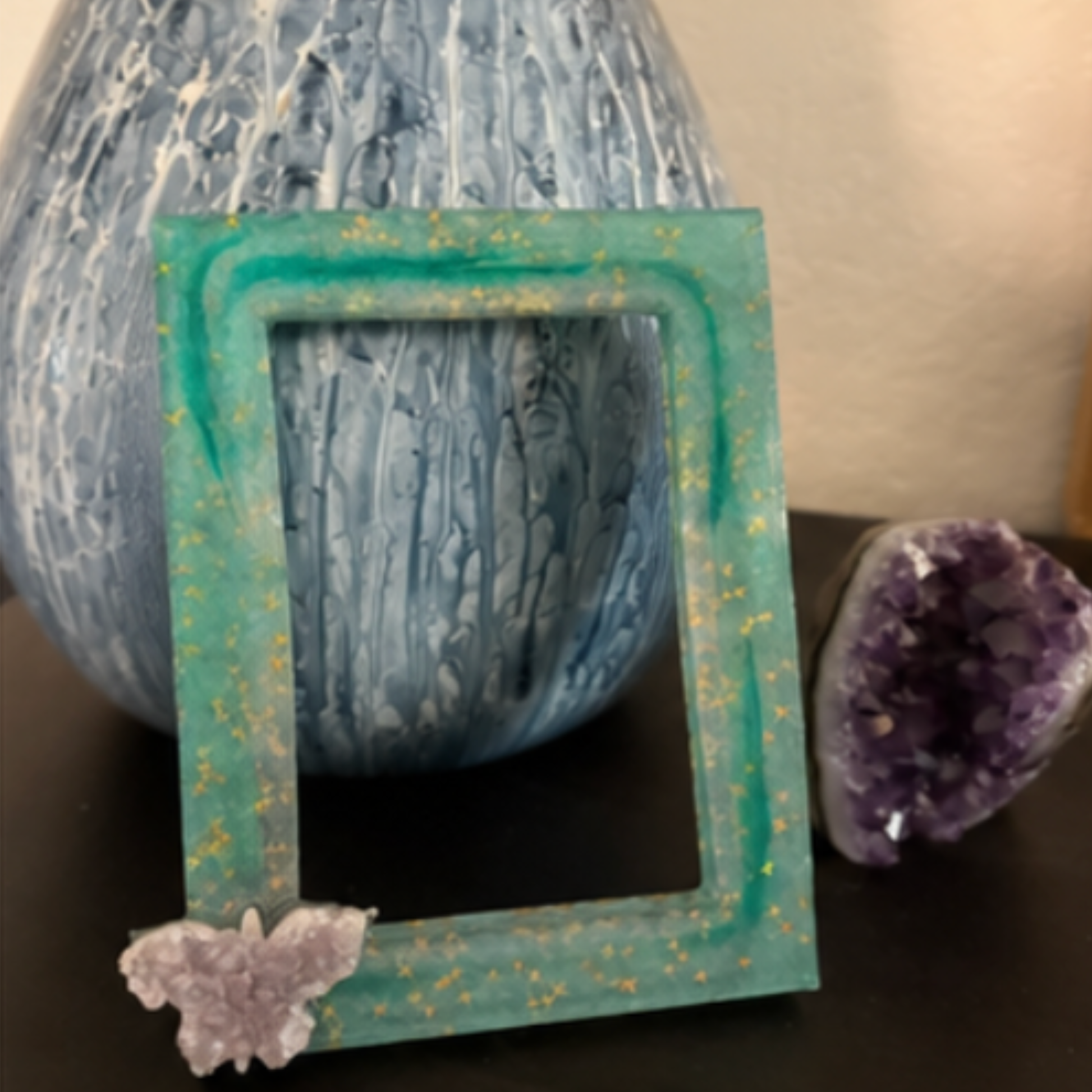 Decorative frame with a textured blue background and amethyst butterfly crystal on a dark surface