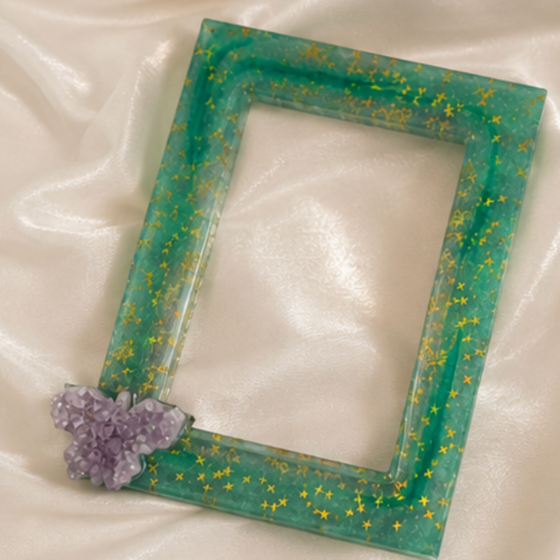 Green decorative picture frame with yellow stars and a amethyst butterfly crystal flower on a white fabric background