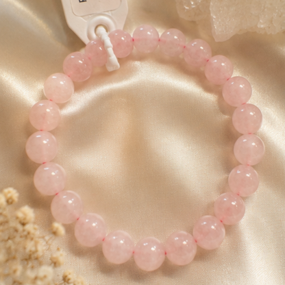 Pink rose quartz beaded bracelet on a beige fabric background